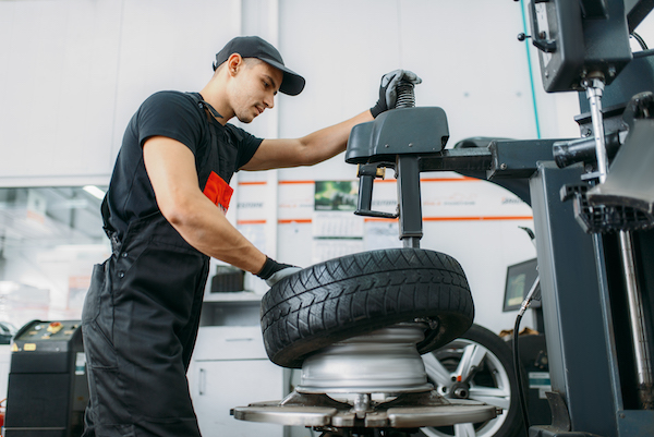 auto mechanic repairing car tire in an auto repair shop