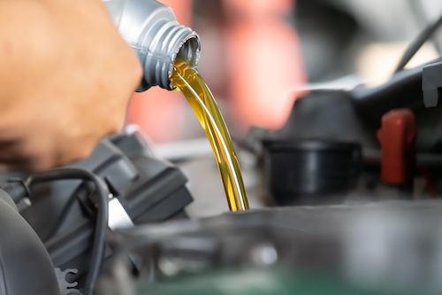 auto mechanic pouring engine oil for an oil change